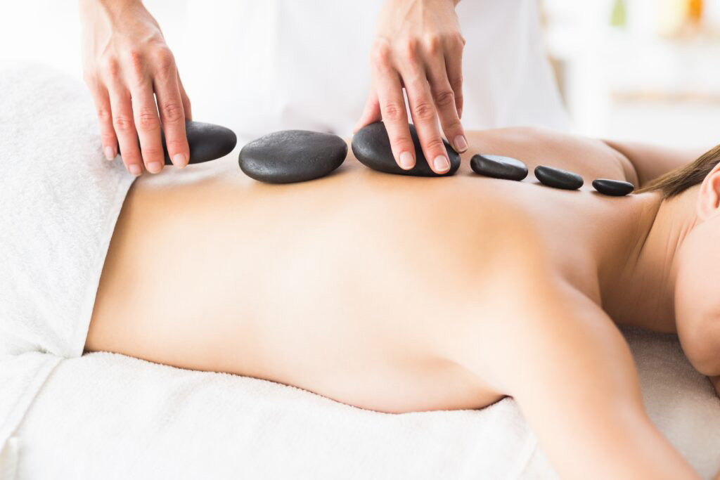 Masseur giving hot stone massage to woman